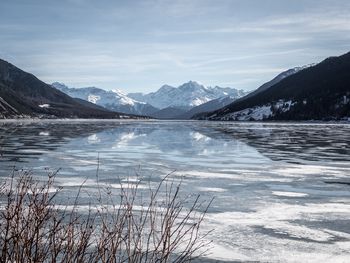 Scenic view of lake by snowcapped mountains against sky