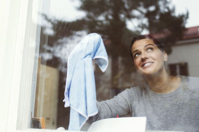 Portrait of woman looking through window