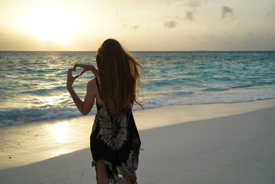 Young woman standing at beach at sunset