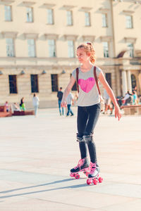 Full length of girl looking away while roller skating in city