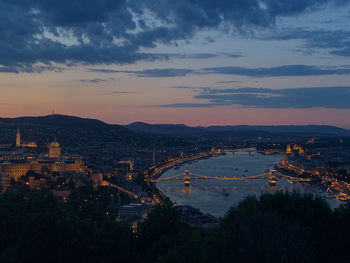 High angle view of illuminated city against cloudy sky