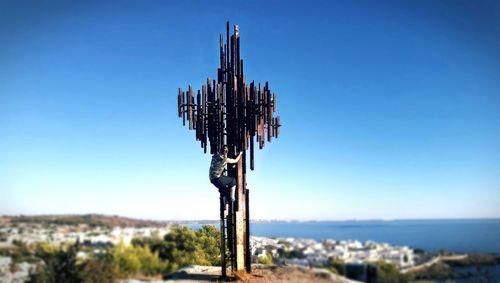 Close-up of wooden post on sea against clear blue sky