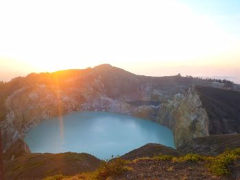 Scenic view of lake and mountains against sky during sunset