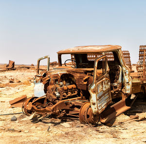 Old abandoned car on field against sky