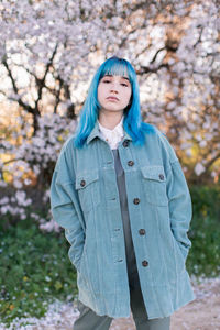 Portrait of beautiful young woman standing against tree