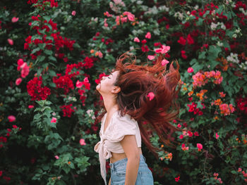 Rear view of young woman standing amidst flowering plants