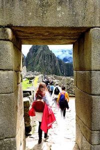 Rear view of people standing on rock against sky