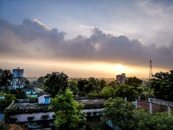 High angle view of trees and buildings against sky at sunset