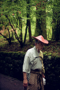 Man wearing hat standing against trees