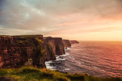 Scenic view of sea and cliff against sky