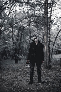 Full length of young man standing on field in forest