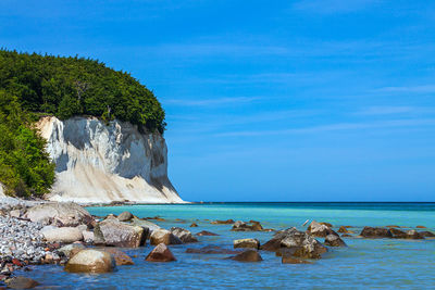 Rocks on beach against blue sky