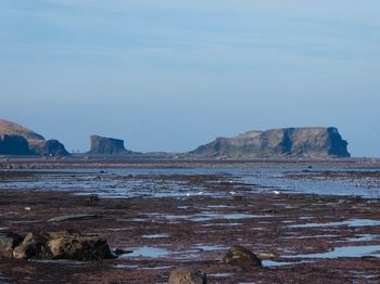 Rock formations on beach against sky