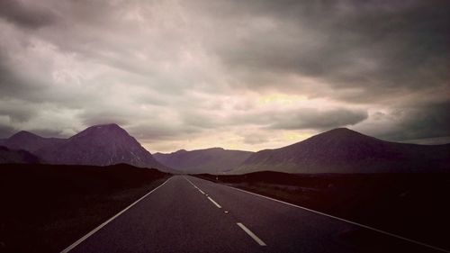 Country road against cloudy sky