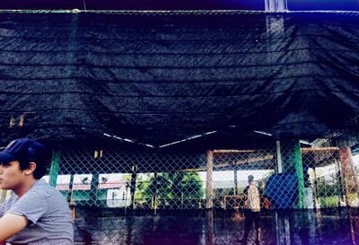 Rear view of man looking through fence