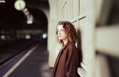 A woman stands near a train at a train station