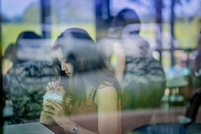 Woman seen through glass window drinking coffee