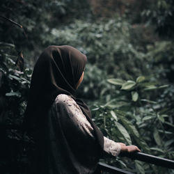 Side view of woman standing by railing in park