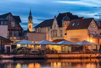 Buildings by river against sky in city