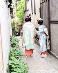 Rear view of women in kimono walking on footpath