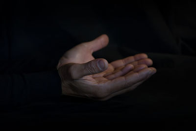 Close-up of human hand against black background