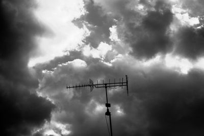 Low angle view of silhouette telephone pole against sky