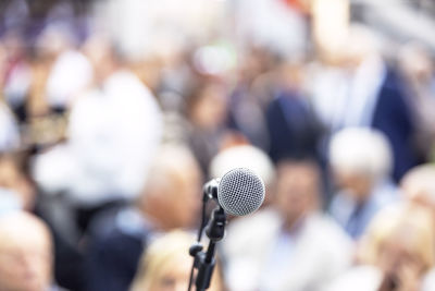 Microphone in the focus, people at publicity event in the background