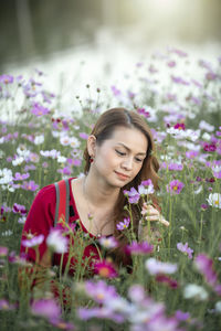 Young woman with pink flowers in sunlight