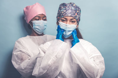 Portrait of doctors wearing mask standing against colored background