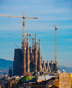 Cranes at construction site against sky in city