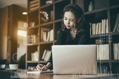 Young woman using mobile phone while sitting on table