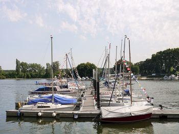 Sailboats moored in river against sky