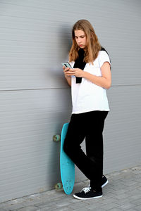 Full length of young woman standing against wall