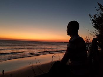 Silhouette woman standing at beach against clear sky during sunset