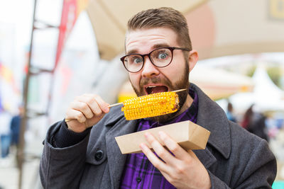 Portrait of man eating corn outdoors