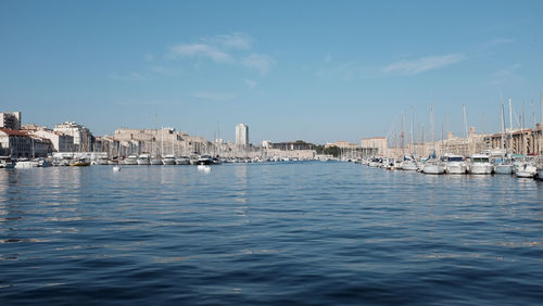 Sailboats in sea by city buildings against sky