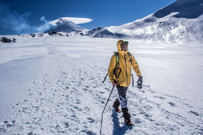 Rear view of man walking on snowcapped mountain