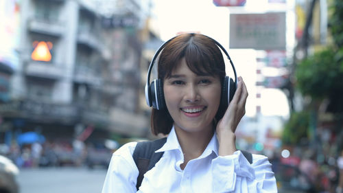 Portrait of a smiling young woman using phone in city