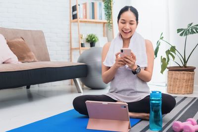 Young woman using phone while sitting on laptop