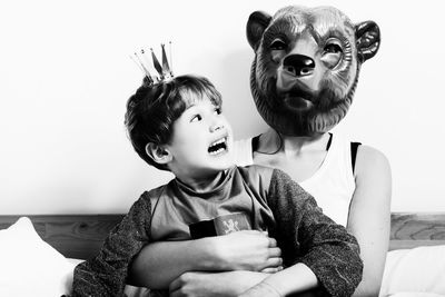 Scared son looking at mother wearing mask at home