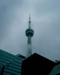 Low angle view of communications tower in city against sky