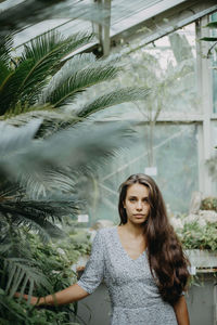 Portrait of beautiful young woman standing by palm trees