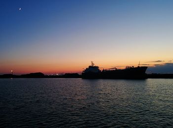 Silhouette ship in sea against clear sky during sunset