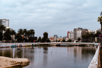 Buildings by river against sky