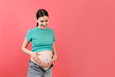 Mid adult woman standing against red background