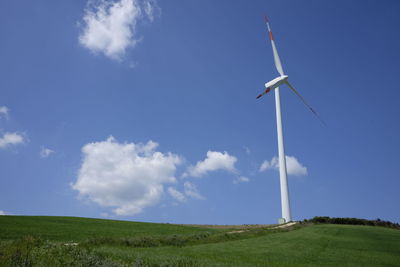 Windmill on grassy field against sky