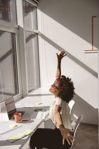 Rear view of woman using mobile phone while sitting at home