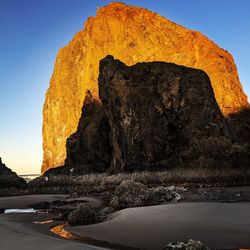 Rock formation in sea against clear sky