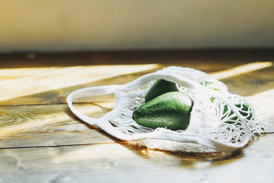 Close-up of avocados with mesh bag on table