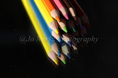 Close-up of multi colored pencils on table against black background